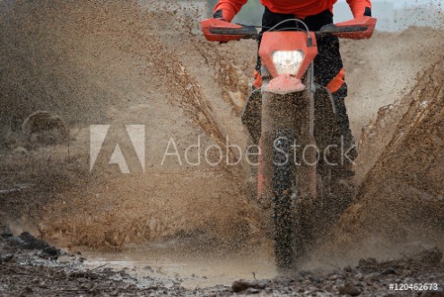 Picture of Motocross driver splashing mud on wet and muddy terrain